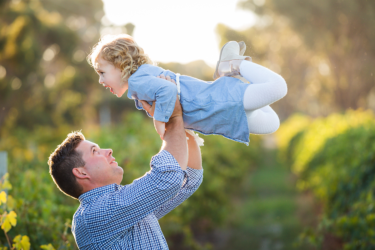 daddy whizzing his little girl around in the vineyards at their family photo shoot by deb elton photography